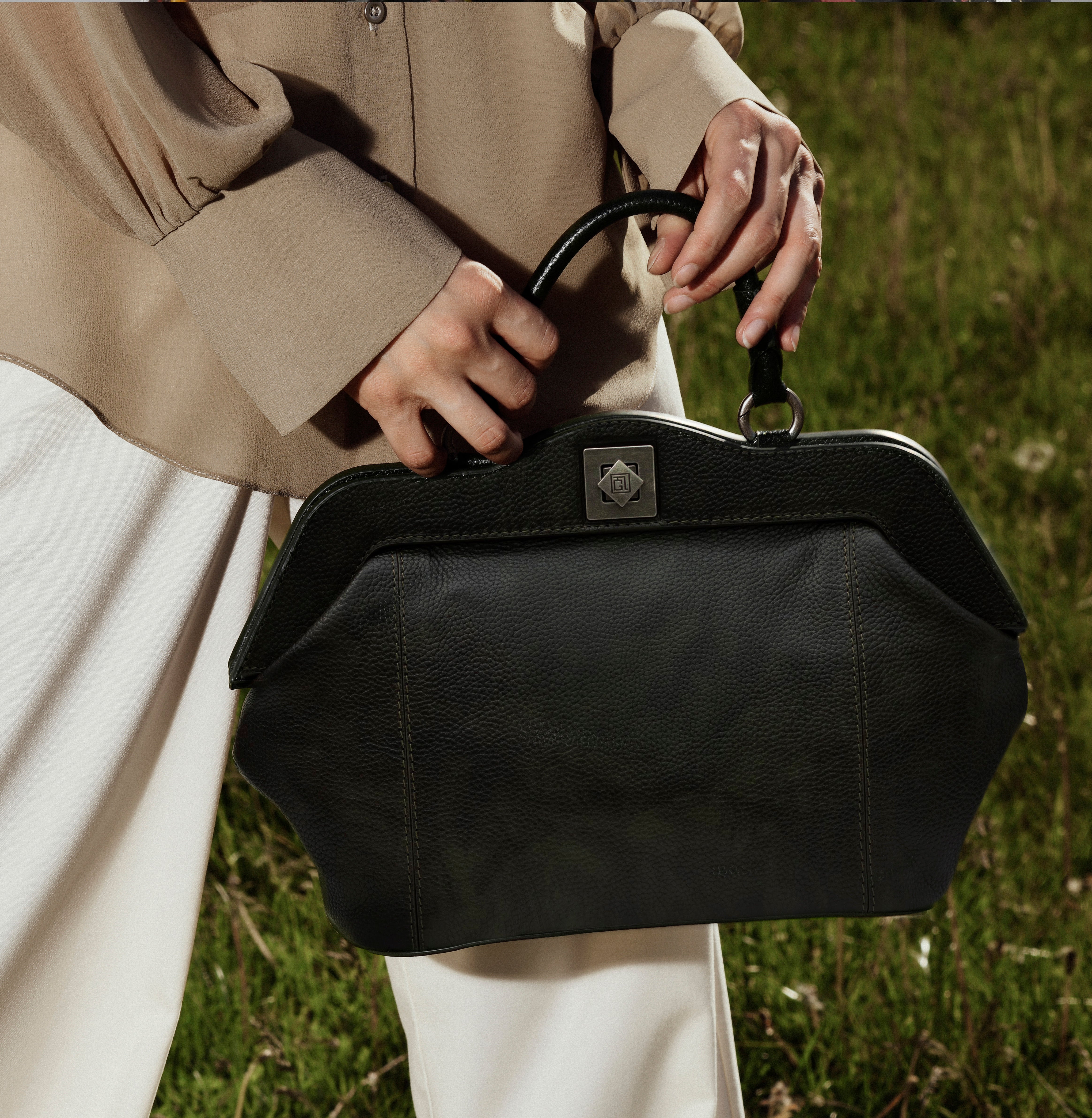 Model carrying Gepherrini Dolly bag in black leather – styled with beige blouse and white trousers