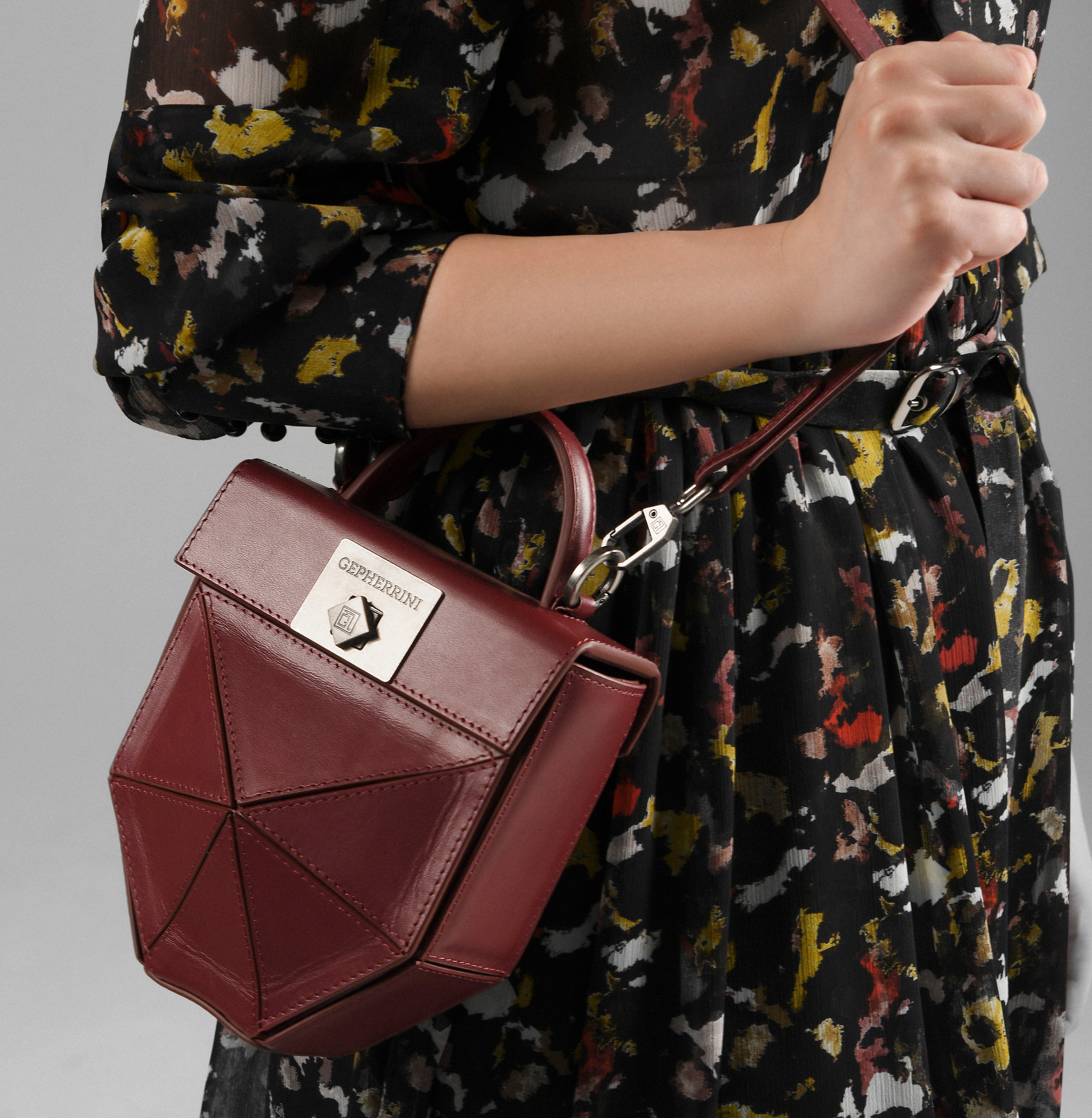 Model holding Gepherrini Isla bag in burgundy with geometric panel design