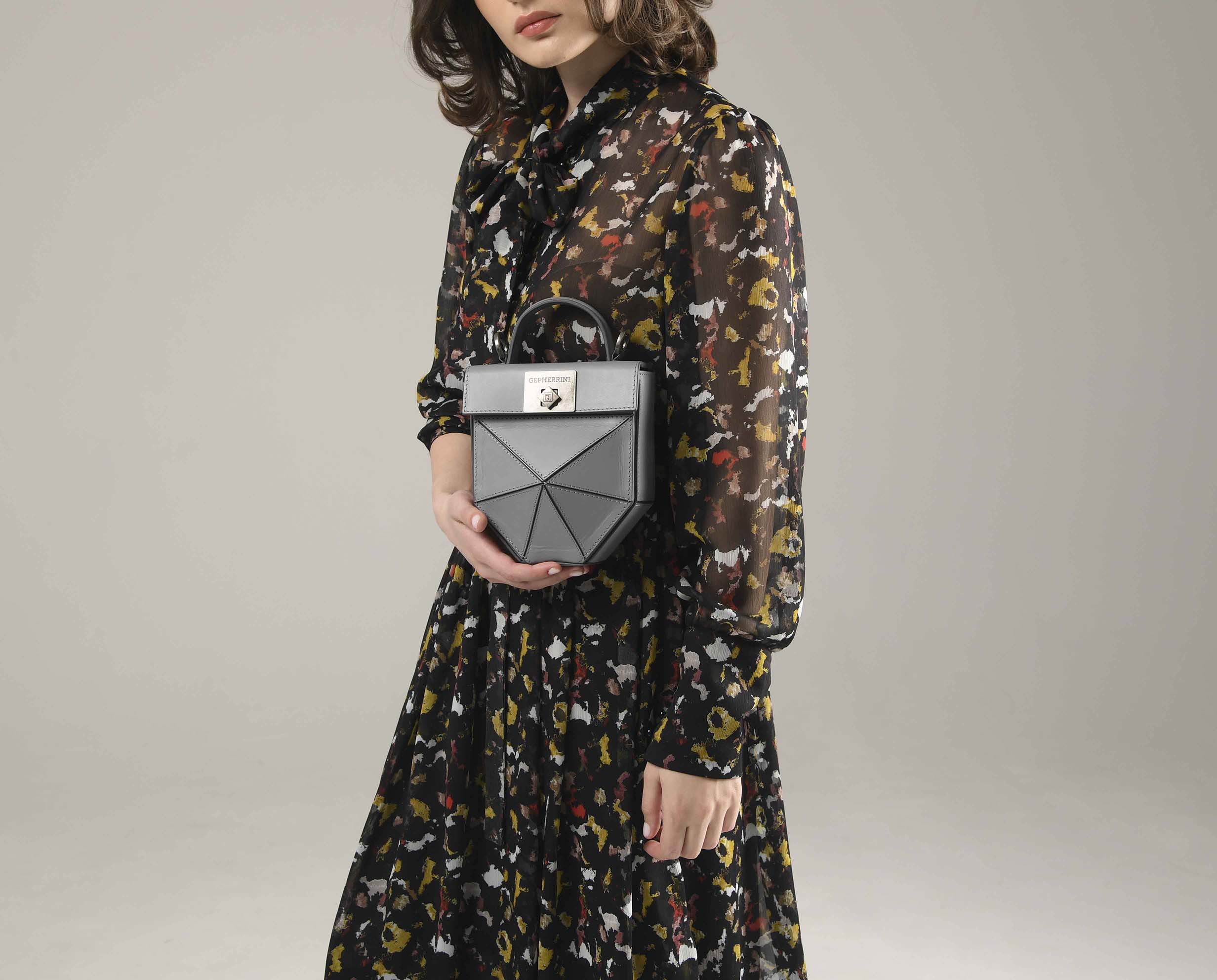 Model holding Gepherrini Isla bag in slate grey with geometric panel design