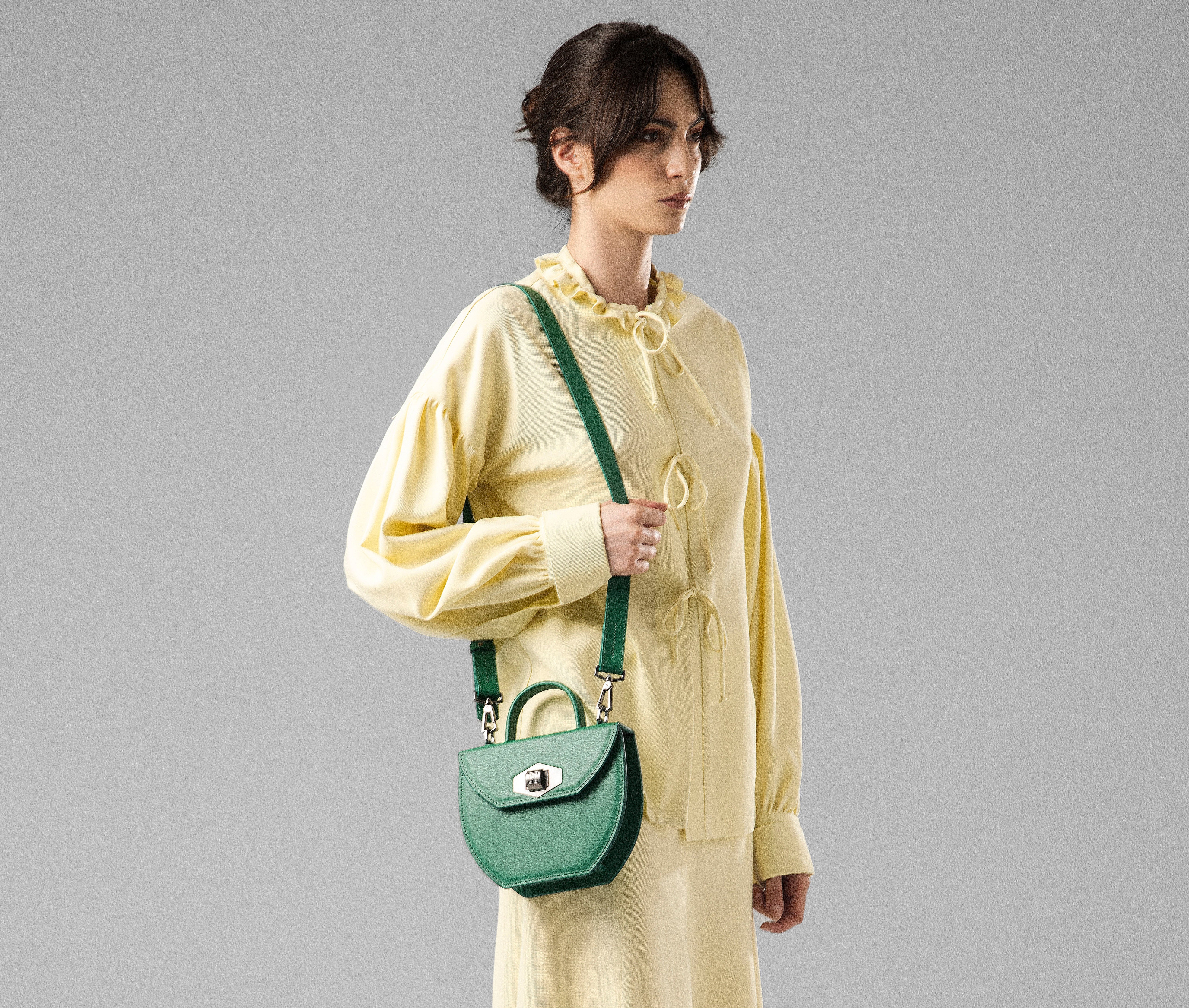 Model wearing pastel yellow dress holding Malisa green handbag on shoulder with strap, styled elegantly