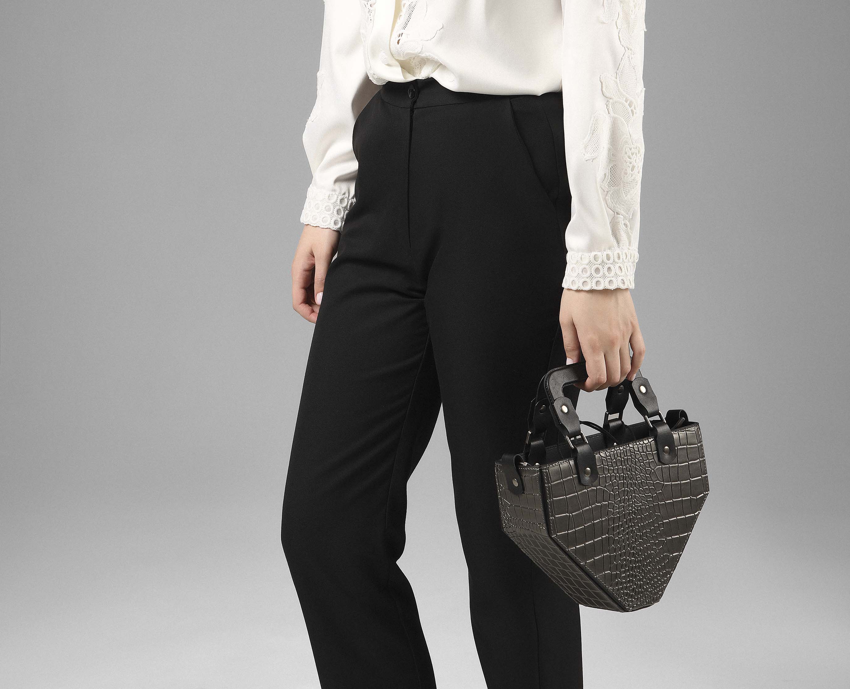 Woman holding Vio brown crocodile-embossed leather handbag styled with monochrome outfit