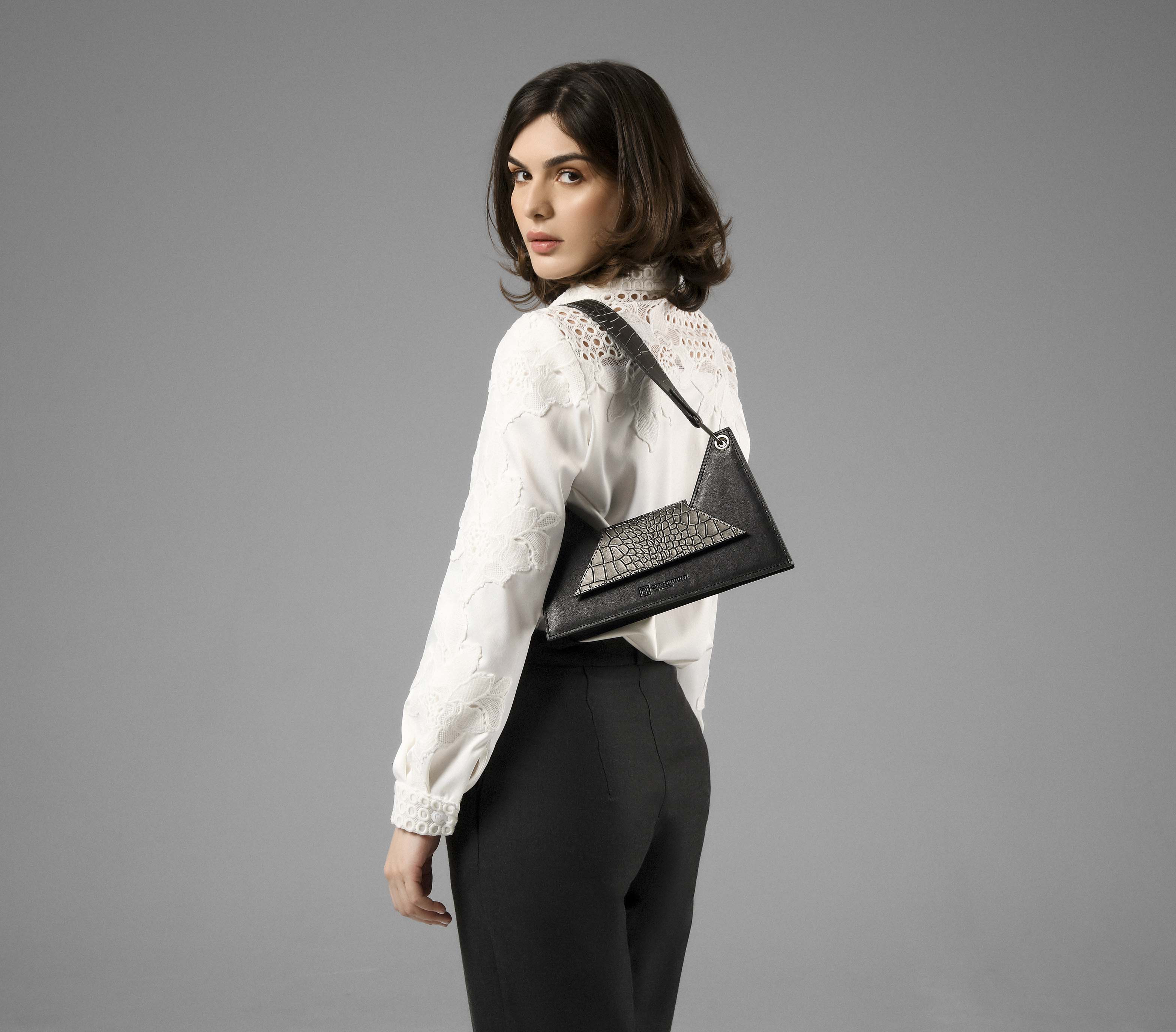 Model holding the Kanna black and gray leather shoulder bag styled with a neutral outfit
